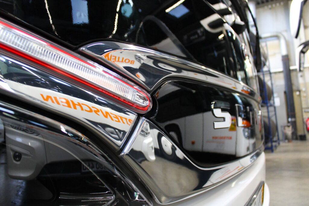 Nahaufnahme eines Bottenschein-Reisebusses mit reflektierenden Oberflaechen in einer Werkstatt.