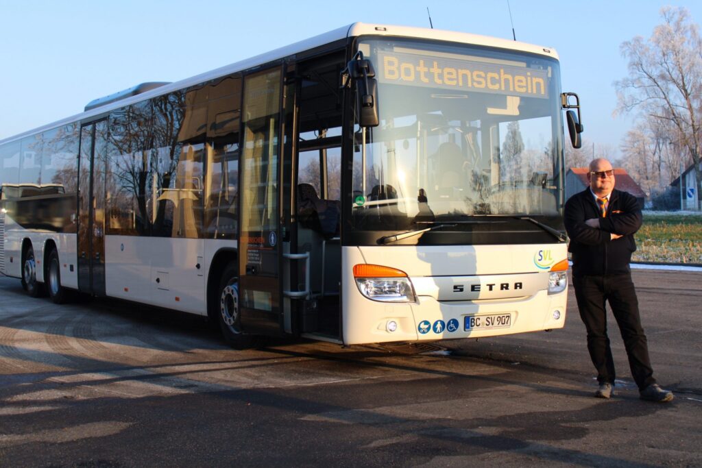 Ein moderner Reisebus mit Fahrer von Bottenschein Reisen auf einem Parkplatz.