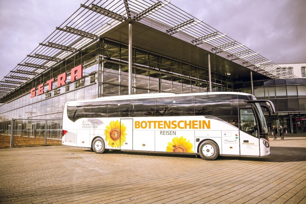 Ein großer Reisebus von Bottenstein-Reisen steht vor einem modernen Gebaeude.