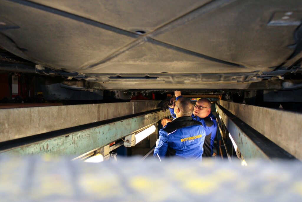Techniker inspiziert den Unterboden eines Reisebusses in der Werkstatt.